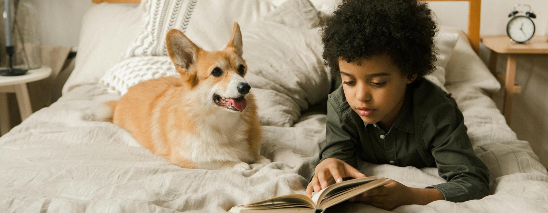 a boy reading a book to a dog
